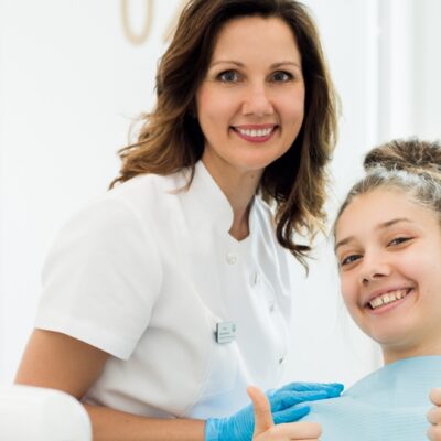 Uśmiechnięta dziewczynka z dentystką dla dzieci w gabinecie stomatologicznym