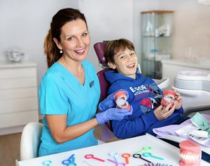Stomatolog dziecięcy z uśmiechniętym chłopcem z odciskiem szczęki do aparatu na fotelu dentystycznym