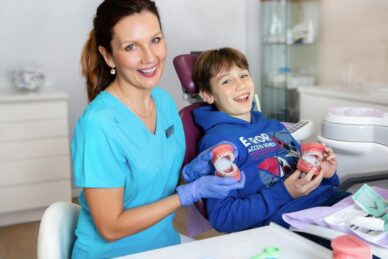 Stomatolog dziecięcy z uśmiechniętym chłopcem z odciskiem szczęki do aparatu na fotelu dentystycznym